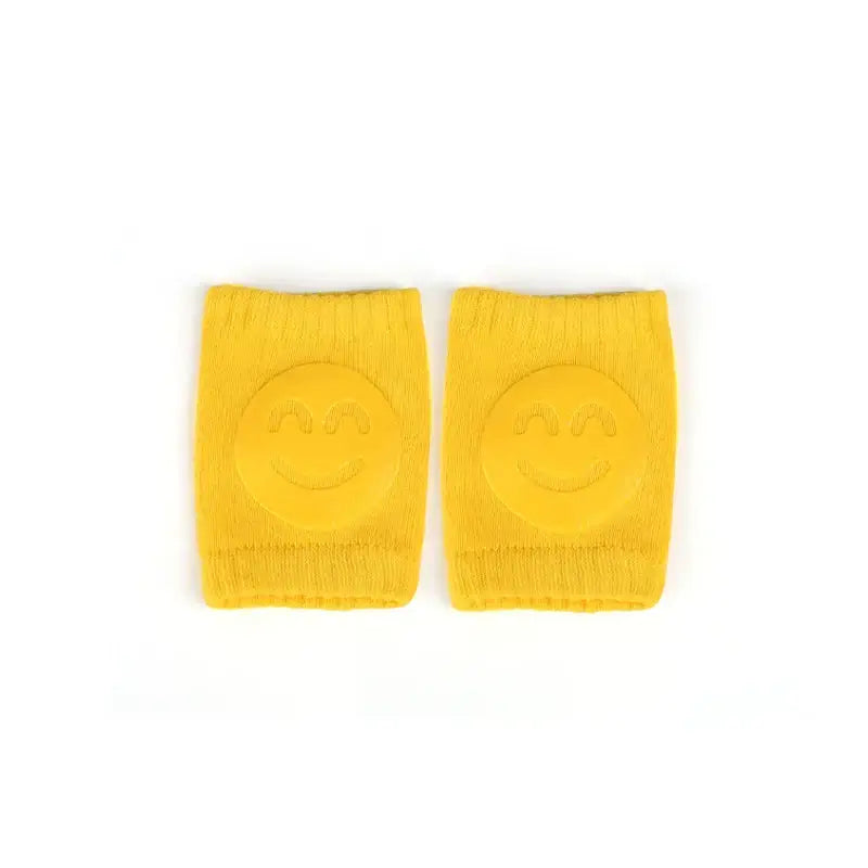 Yellow baby knee pads with smiley face design for crawling infants and toddlers, perfect for leg protection.