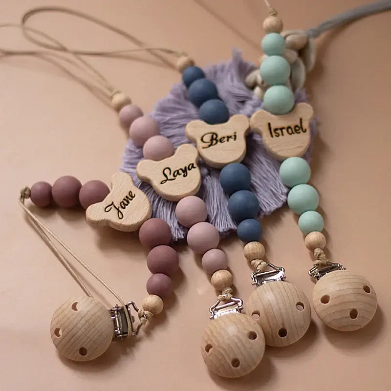 Personalized wooden baby pacifier chains with silicone beads and names, ideal for newborn gifts and teething.
