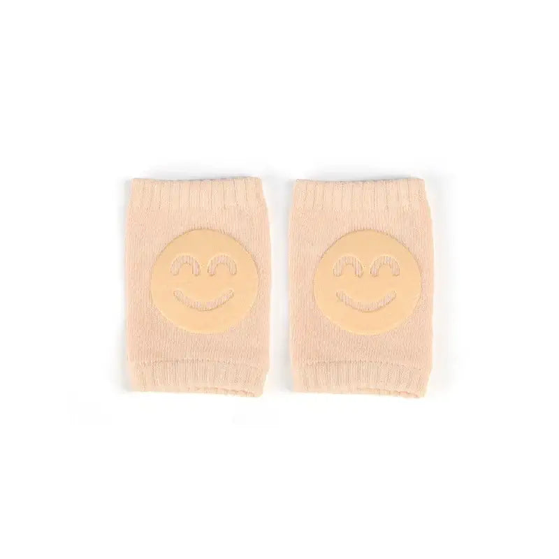 Baby knee pads with smiley face design, non-slip crawling cushion for infants and toddlers, beige color.
